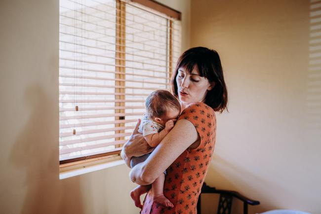Mother shushing a new baby as she holds her during a Perth lifestyle Newborn photography session