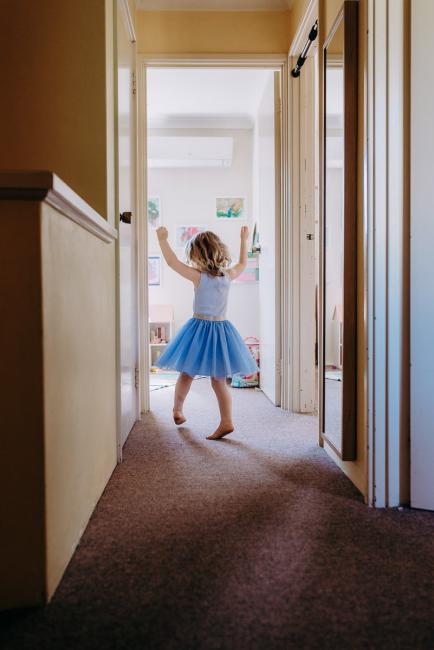 Little girl twirling and dancing in the doorway during a Perth family lifestyle photography session