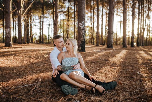 Perth-Couples-Photography-10-of-27 Couple sitting down with the woman between his legs at The Pines Wanneroo during a Golden Hour Perth couples photography session