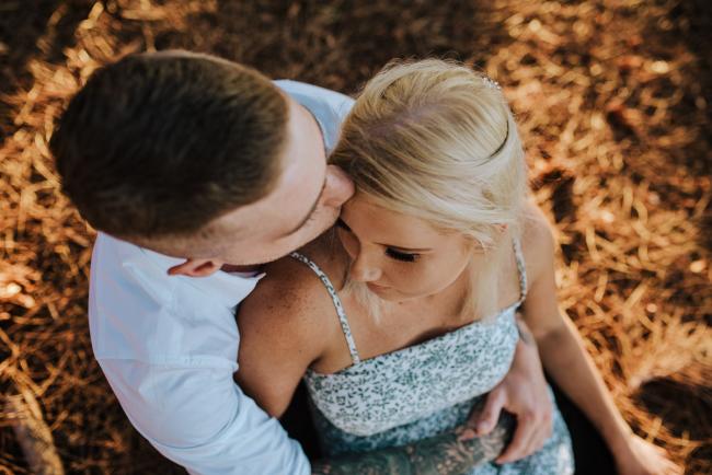 Perth-Couples-Photography-11-of-27 Top down image of a couple sitting together as the man kisses her forehead at The Pines Wanneroo during a Golden Hour Perth couples photography session