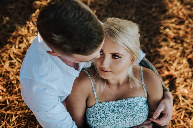 Perth-Couples-Photography-12-of-27 Top down image of a couple sitting together as she looks up into his eyes and he looks down on her at The Pines Wanneroo during a Golden Hour Perth couples photography session
