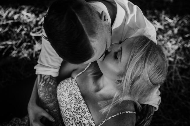 Perth-Couples-Photography-13-of-27 Black and white top down image of a couple sitting and kissing at The Pines Wanneroo during a Golden Hour Perth couples photography session