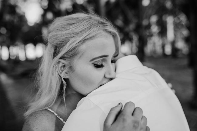 Black and white close up of a woman embracing her partner during a Perth couples photography session at The Pines in Wanneroo