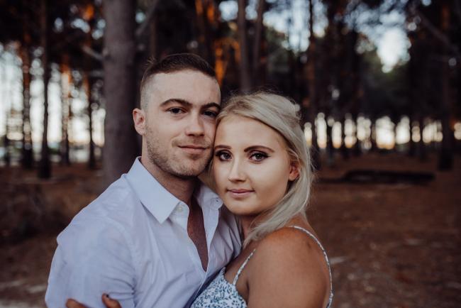 Perth-Couples-Photography-18-of-27 Close up of a couple looking at the camera with their heads next to each other at The Pines Wanneroo during a Golden Hour Perth couples photography session