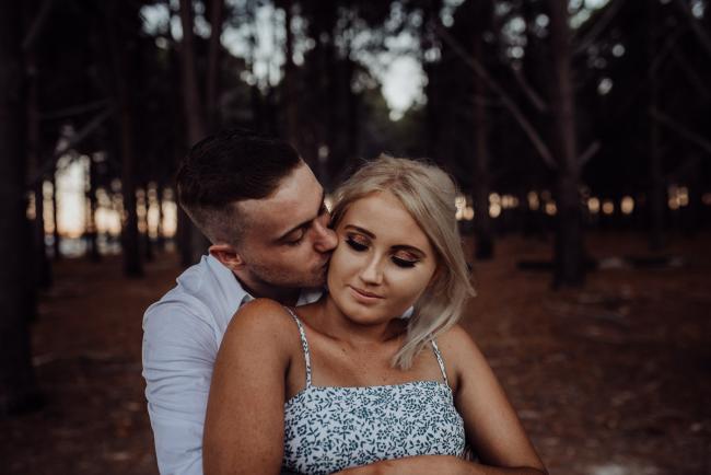 Man hugging his girlfriend from behind during a Perth couples photography session at The Pines in Wanneroo