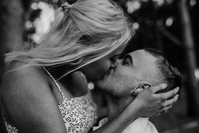 Perth-Couples-Photography-27-of-27 Black and white image of a woman holding her partners head as they kiss at The Pines Wanneroo during a Golden Hour Perth couples photography session