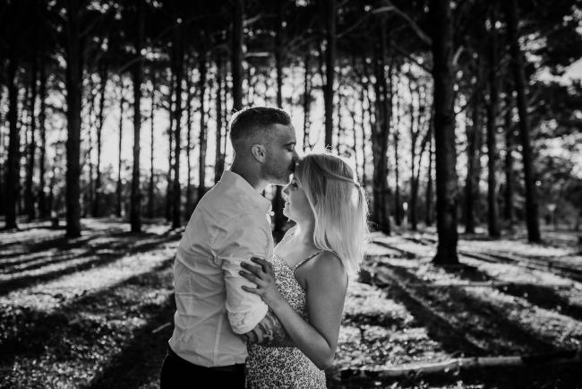 Perth-Couples-Photography-3-of-27 Black and white image of a man kissing the forehead of his partner at The Pines Wanneroo during a Golden Hour Perth couples photography session