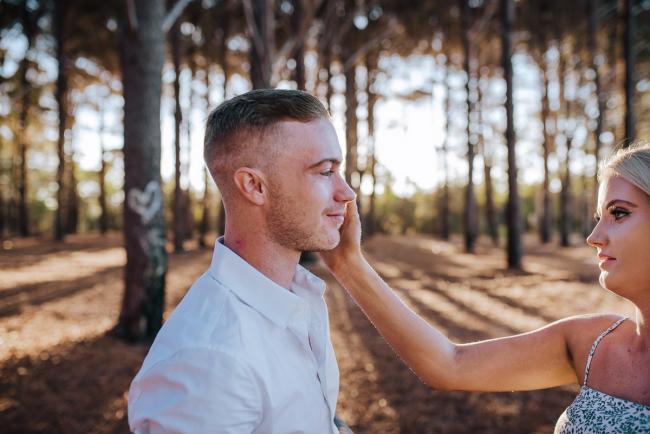 Perth-Couples-Photography-8-of-27 Woman reaching into the frame and touching her partners face at The Pines Wanneroo during a Golden Hour Perth couples photography session