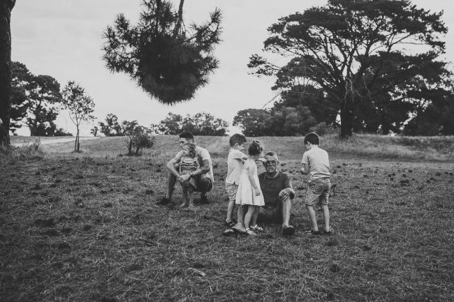Black and white image of children playing with their grandfather during a Perth extended family photography session