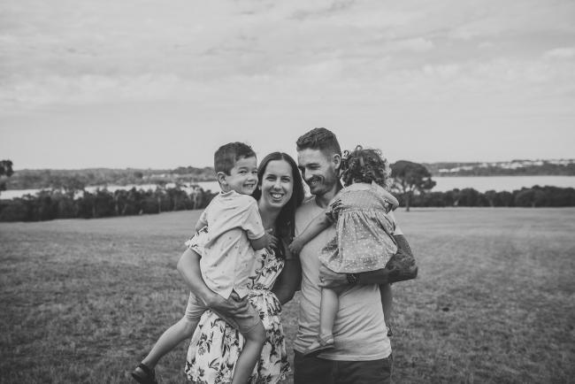 Black and white image of a family of 4 with mother holding the son and father holding his daughter during a Perth extended family photography session