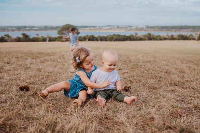 Little girl and boy sitting next to each other on the grass during a Perth extended family photography session