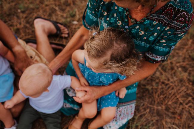 Top down image of a little girl sitting on her grandmothers lap with her baby cousin next to her during a Perth extended family photography session
