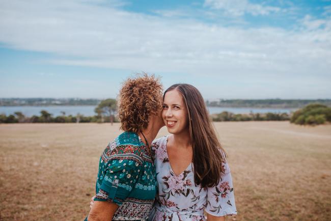 Older daughter and mother during a Perth extended family photography session with the mother kissing her daughter as the daughter looks at the camera