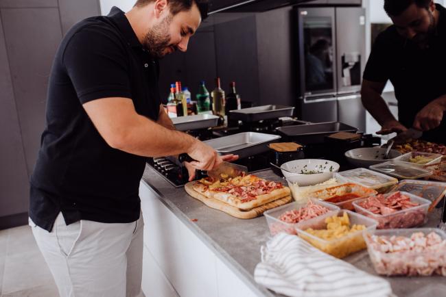 Man preparing pizza in the kitchen during a birthday party captured by Perth events photographer