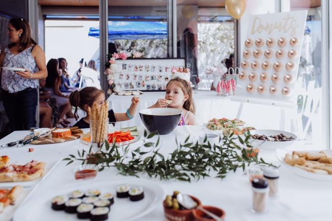 Two little girls taking food from the table during a birthday party captured by Perth events photographer