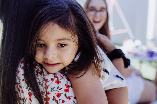 Little girl cuddling on the shoulder of a woman during a birthday party captured by Perth events photographer