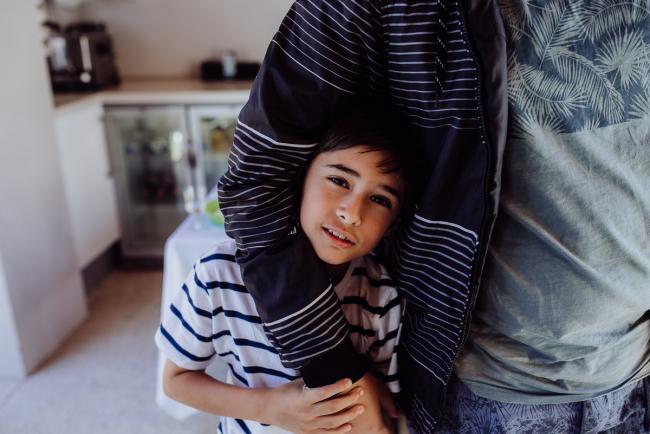 Little boy tucked under the arm of his older cousin during a birthday party captured by Perth events photographer