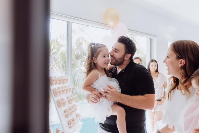 Father kissing his little girl who he is carrying during a birthday party captured by Perth events photographer