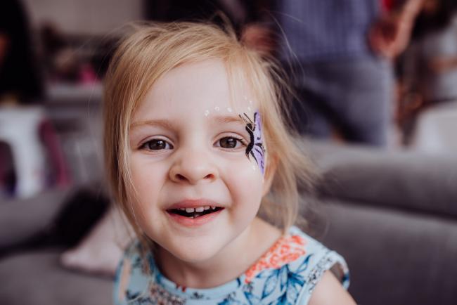 Little girl with butterfly face paint looking at the camera during a birthday party captured by Perth events photographer