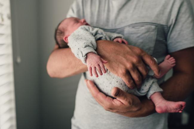 Close up of new baby in dad's arms during a Perth lifestyle newborn photography session