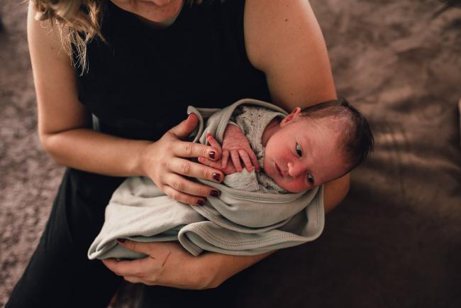 Top down image of new baby wrapped up in mum's arms during a Perth lifestyle newborn photography session