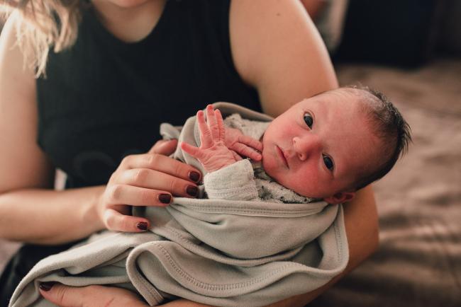 New baby in mum's arms during a Perth lifestyle newborn photography session