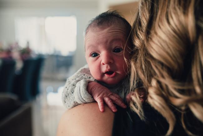 New baby looking over mum's shoulder during a Perth lifestyle newborn photography session