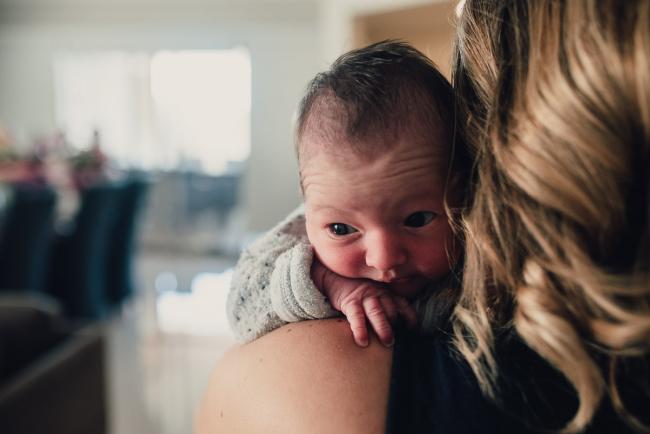 New baby looking over mum's shoulder during a Perth lifestyle newborn photography session