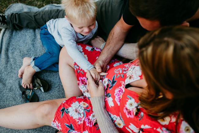 Top down image of a mother, father and little boy touching the mother's pregnant tummy during a Perth maternity session at Hyde Park