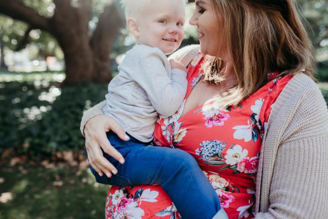 Little boy sitting on top of his mother's pregnant tummy during a Perth maternity session at Hyde Park