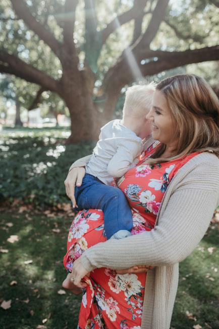 Pregnant mother holding her toddler son as she laughs during a Perth maternity session at Hyde Park