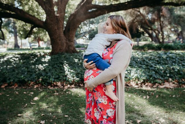 Pregnant mother holding her little boy on her tummy during a Perth maternity session at Hyde Park