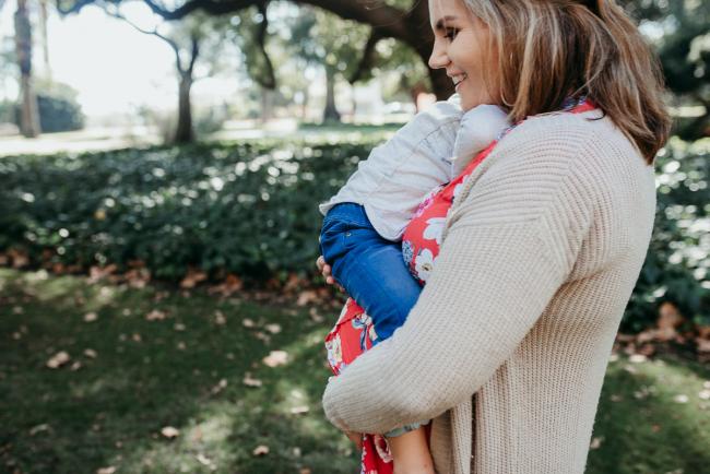 Little boy cuddling his mother as she carries him on top of her pregnant tummy during a Perth maternity session at Hyde Park