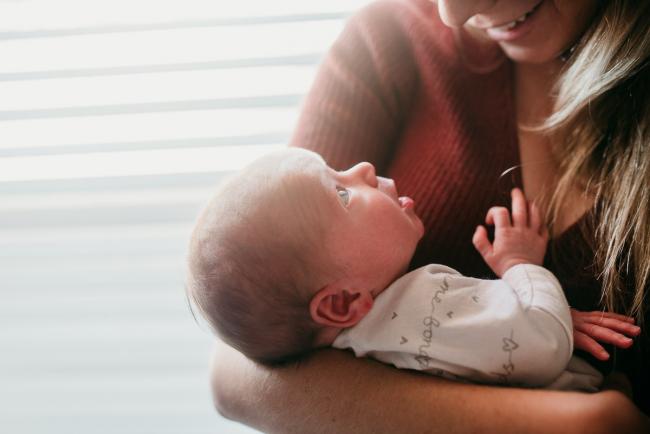 Newborn-Photographer-Perth-1-of-37 Newborn baby looking up at her mother while her mother is holding her in her arms with Perth lifestyle newborn photographer