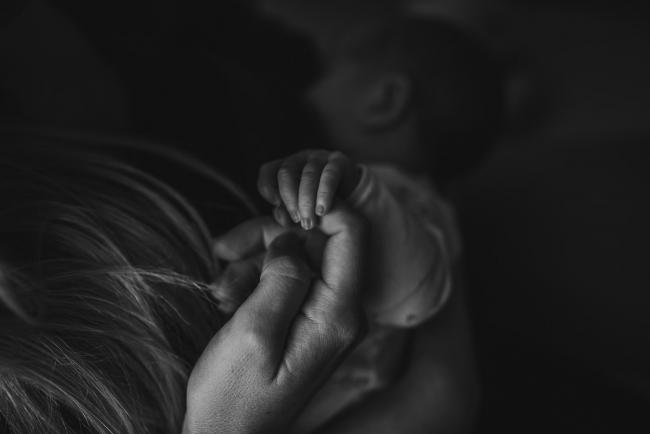 Newborn-Photographer-Perth-12-of-37 Black and white image of mother holding the hand of the newborn baby during a Perth newborn lifestyle session