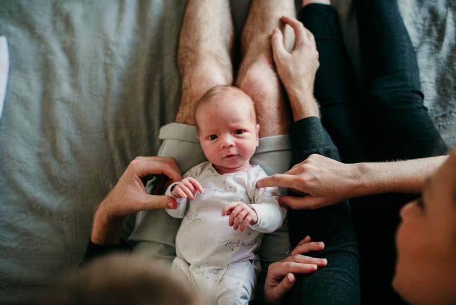 Newborn-Photographer-Perth-16-of-37 Newborn baby laying on the lap of her parents during a Perth newborn lifestyle session