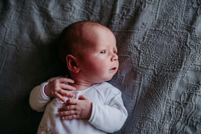 Newborn-Photographer-Perth-20-of-37 Newborn baby on a bed looking to the side during a Perth newborn lifestyle session