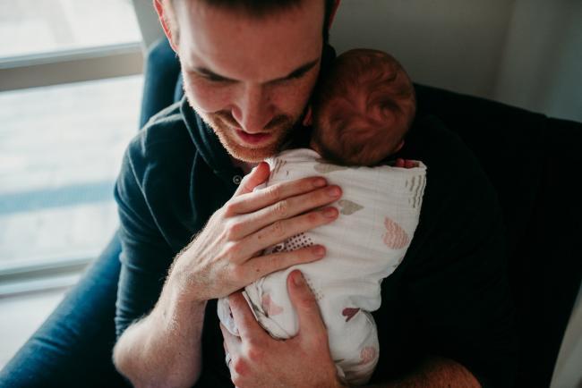 Father holding his newborn baby up to his chest during a Perth newborn lifestyle session