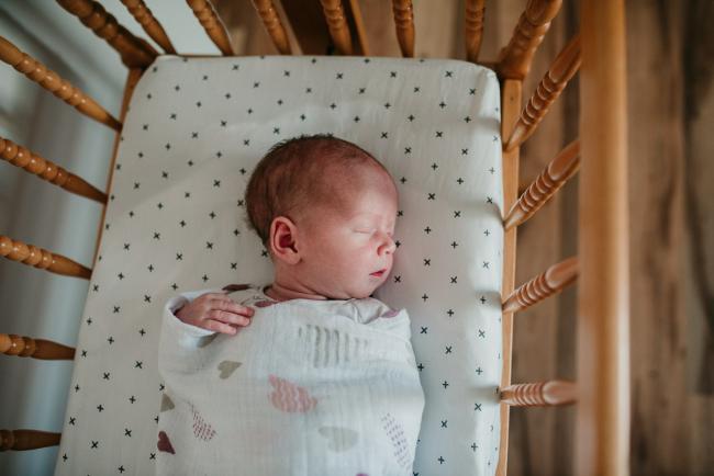 Newborn-Photographer-Perth-30-of-37 Top down image of a new baby laying in her bassinet during a Perth newborn lifestyle session