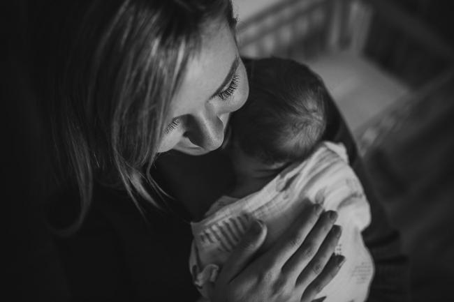 Newborn-Photographer-Perth-32-of-37 Black and white image of mother holding her newborn baby on her chest during a Perth newborn lifestyle session