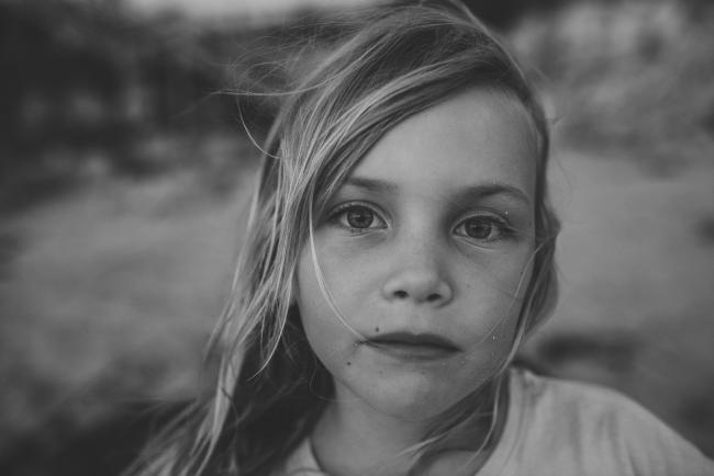 Black and white image of little girl looking at the camera at Burns Beach during a Perth family photography session