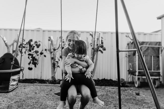 20190406-DSC_0126 Black and white photo of girl holding a little boy on her lap on the swing with Perth lifestyle family photographer