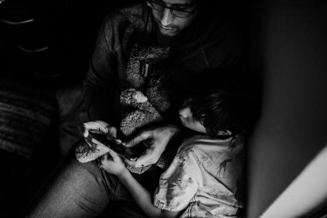 20190419-DSC_1769 Black and white image of boy laying on his dad as they look at his phone with Perth family photographer