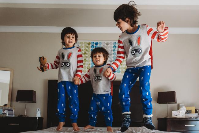 20190422-DSC_2294 Three boys in matching pyjamas holding hands and jumping on the bed with family photographer Perth