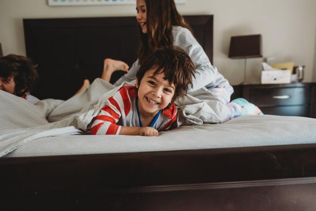 20190422-DSC_2450 Boy smiling on the bed with his siblings around him with family photographer Perth