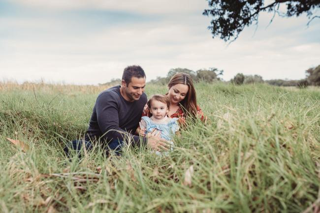 Parents sitting in the grass with their little girl with Perth family photographer at Perry's Paddock
