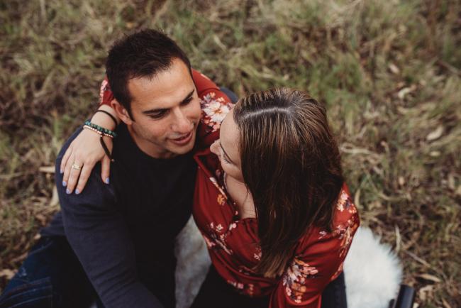 Top down image of wife with her arms around her husband as they sit on the grass with Perth family photographer at Perry's Paddock