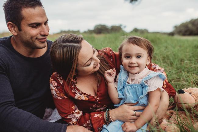 Parents smiling at their little girl who is smiling at the camera with Perth family photographer at Perry's Paddock