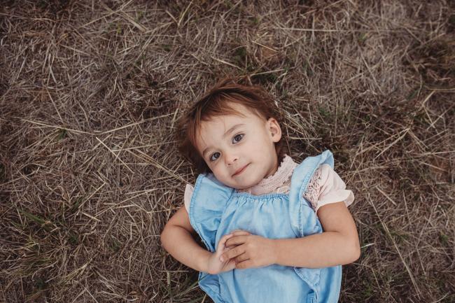 Little girl laying on the grass with Perth family photographer at Perry's Paddock