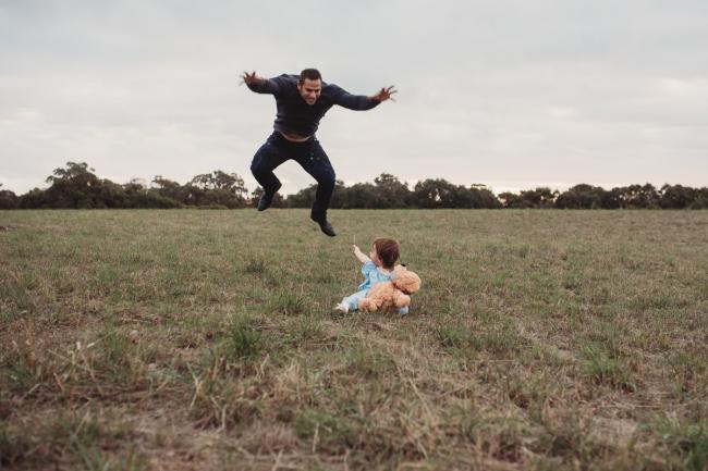 Father jumping behind his daughter with Perth family photographer at Perry's Paddock